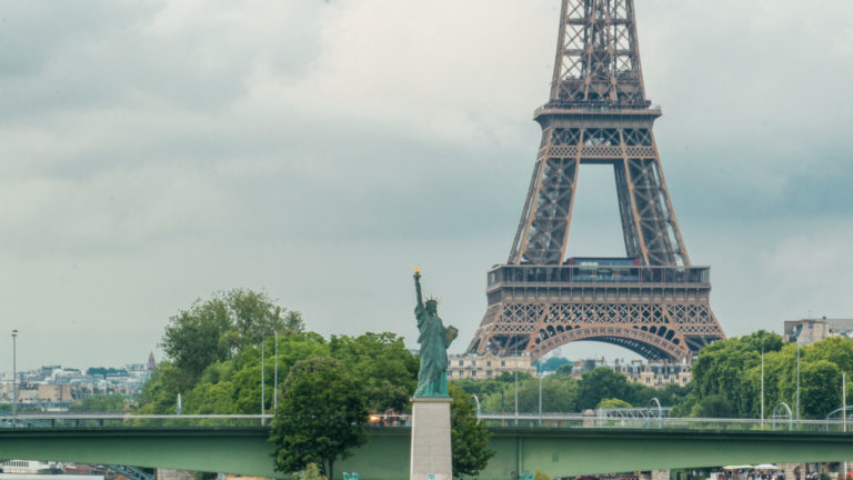 Une statue de la liberté en face de la Tour Eiffel.
